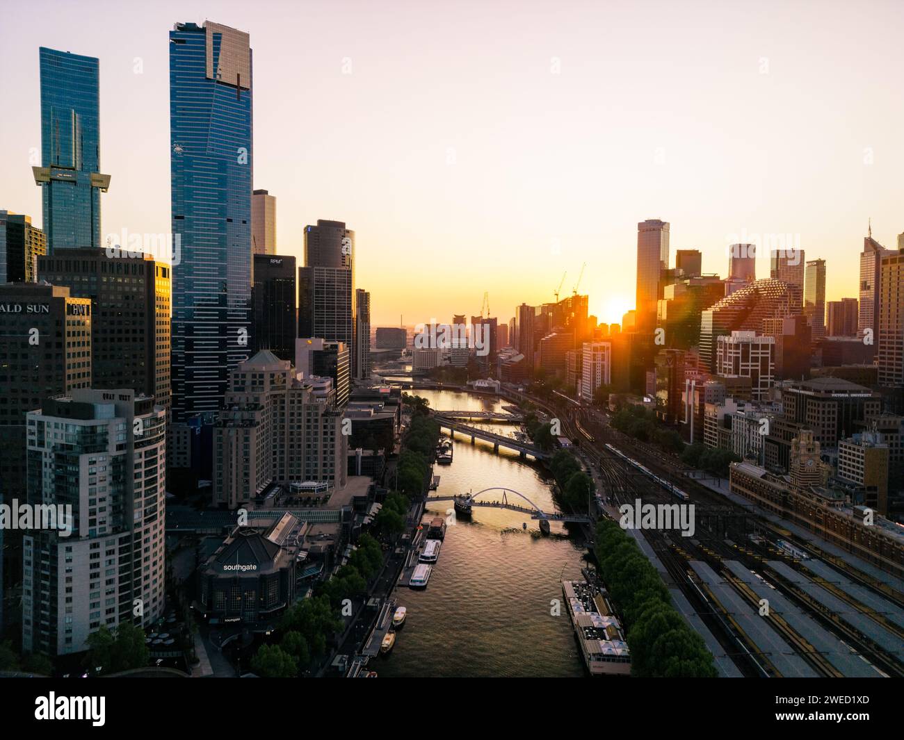 A view of the Yarra River flanked my tall city buidlings, boats moored on the banks and walk bridges taken at sunset in Melbourne, Australia. Stock Photo