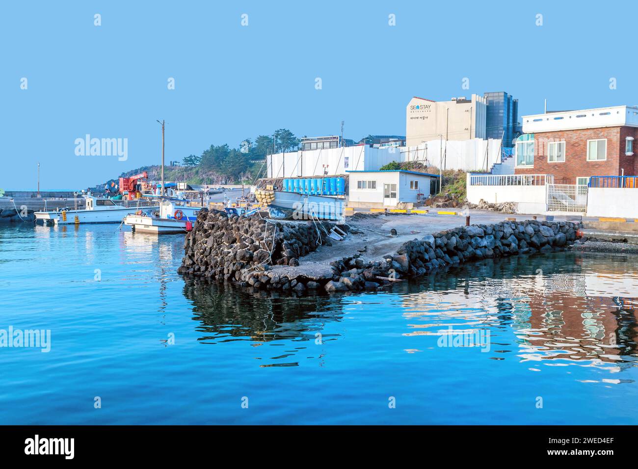 Landscape of small fishing port on calm morning under blue sky in Jeju, South Korea Stock Photo