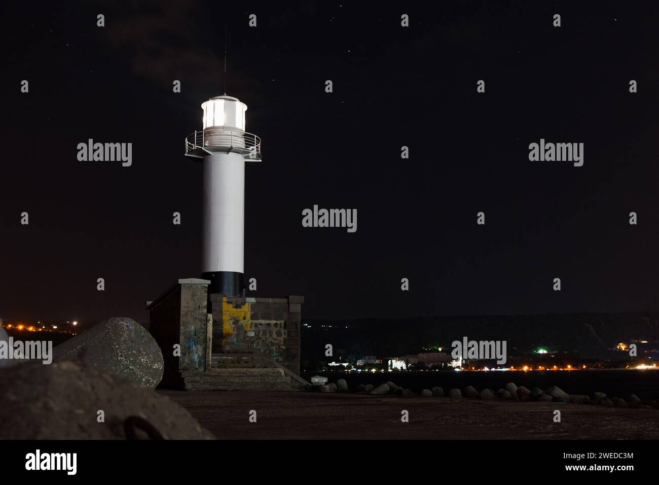 White lighthouse tower with glowing light. Night photo taken at Port of Varna, Bulgaria Stock Photo