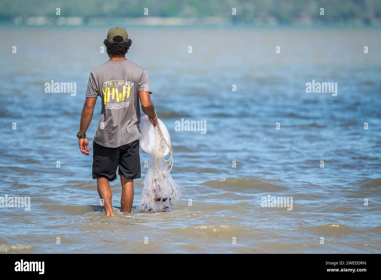 A good, young man stands knee deep in the sea with cast net in hand searching for food for his body and baring his deep 'faith' and conviction. Stock Photo