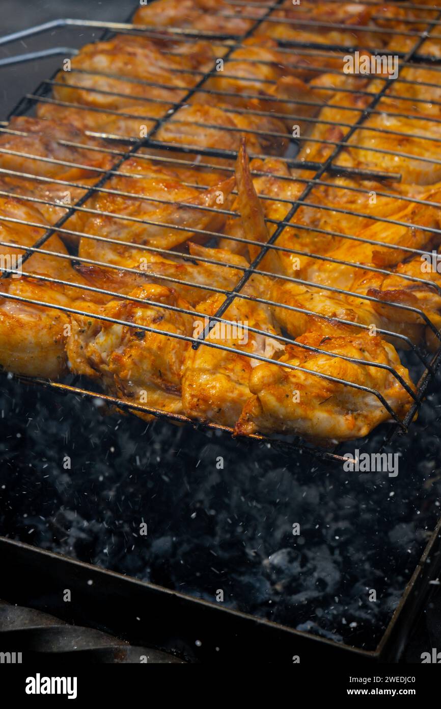 Delicious chicken frying on barbecue grill grate outdoor. Seasoning