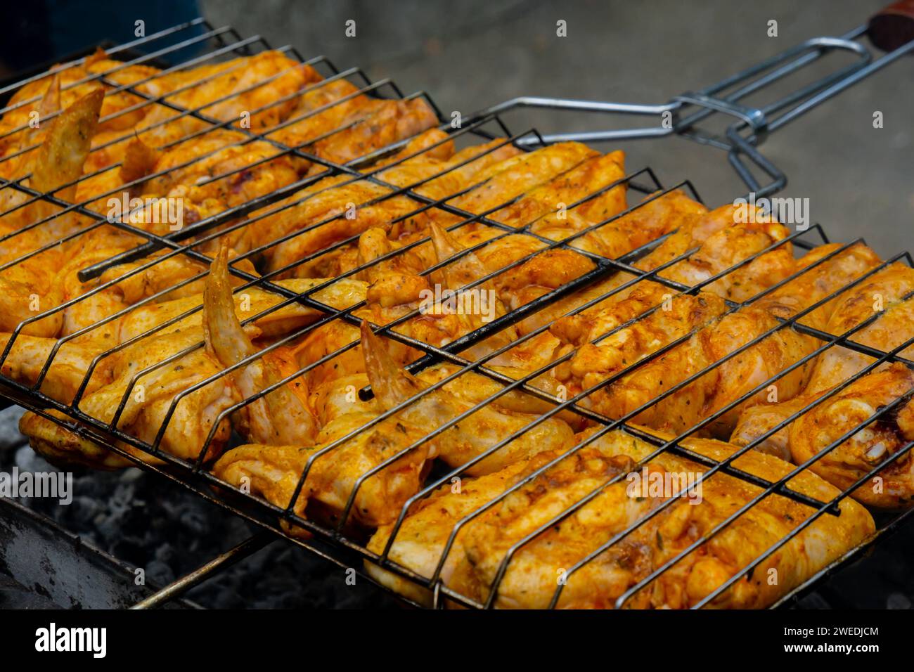 Delicious chicken frying on barbecue grill grate outdoor. Seasoning