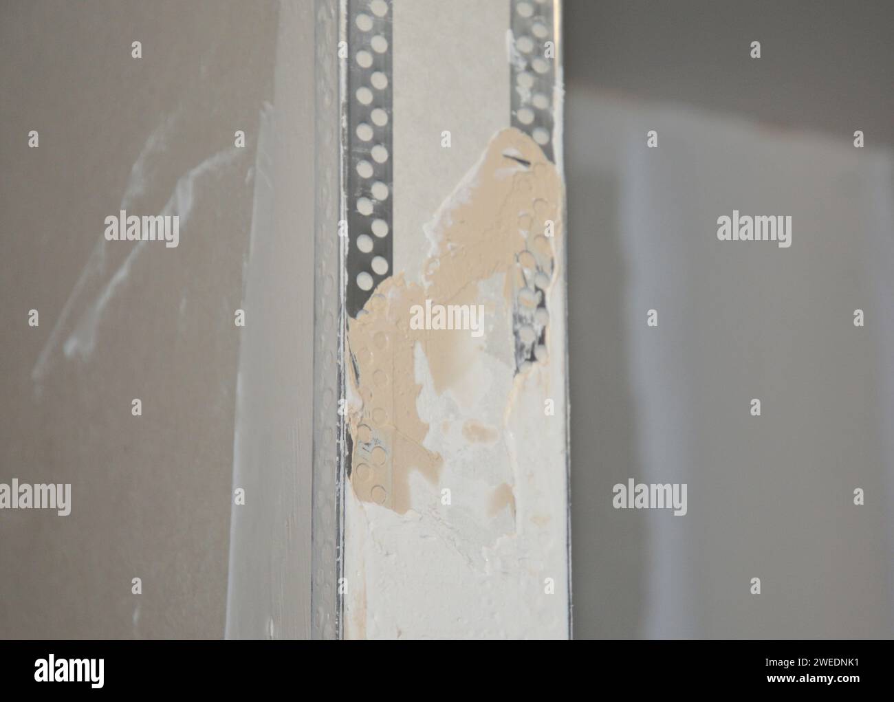 Plastering drywall corner: A close-up on plastering a drywall partition wall over installed angle beads during house renovation. Stock Photo