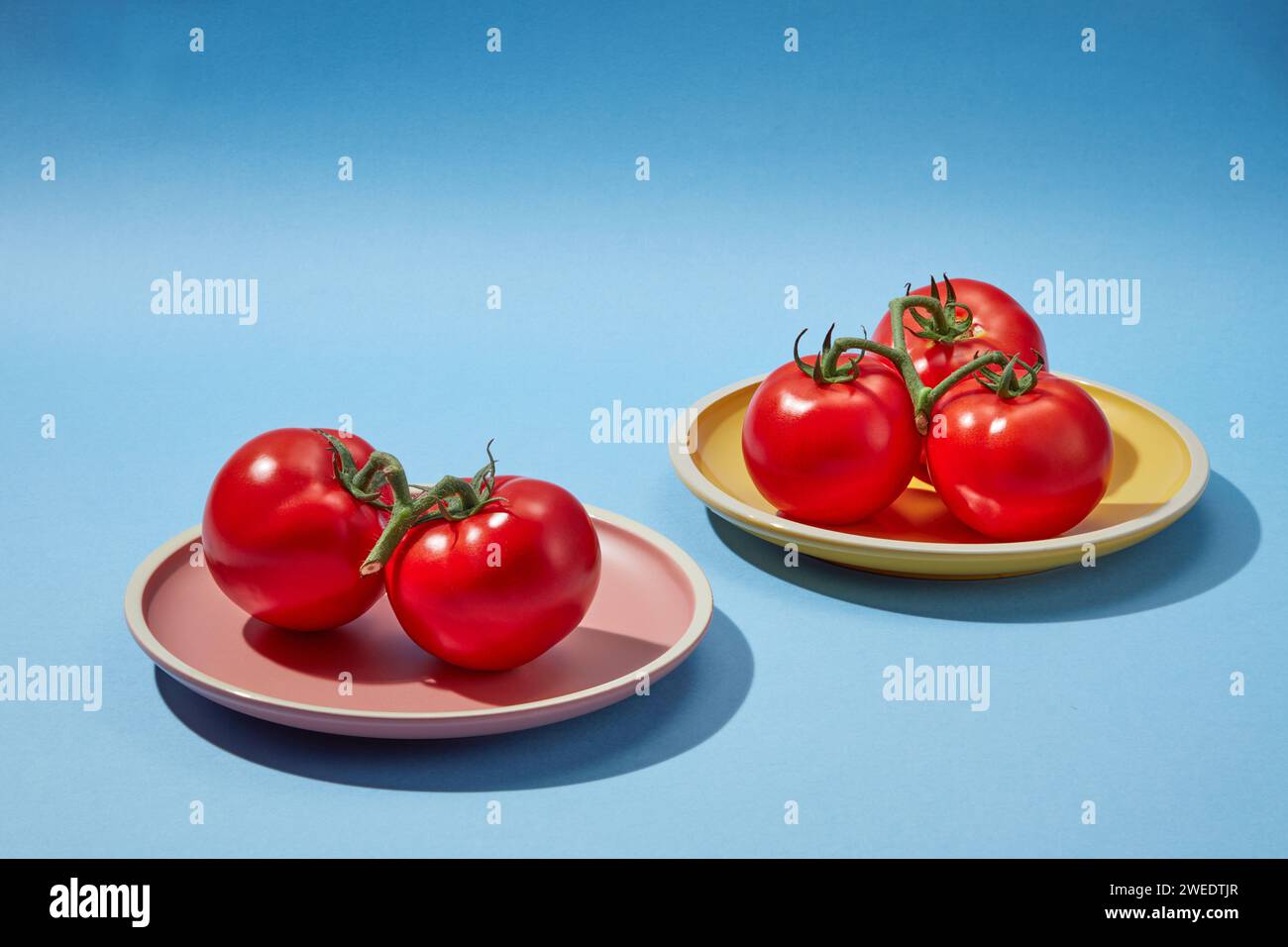 Scene for advertising cosmetic products of tomato extract - round plated containing red fresh tomatoes on a blue background. Tomatoes have a lot of nu Stock Photo