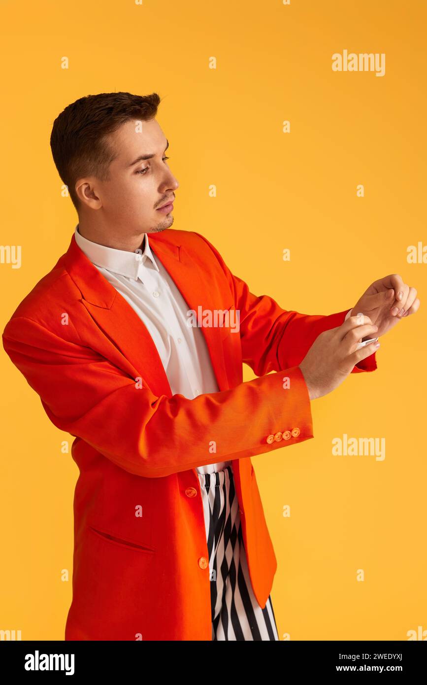 Cheerful funny young man in orange jacket and striped pants on yellow ...