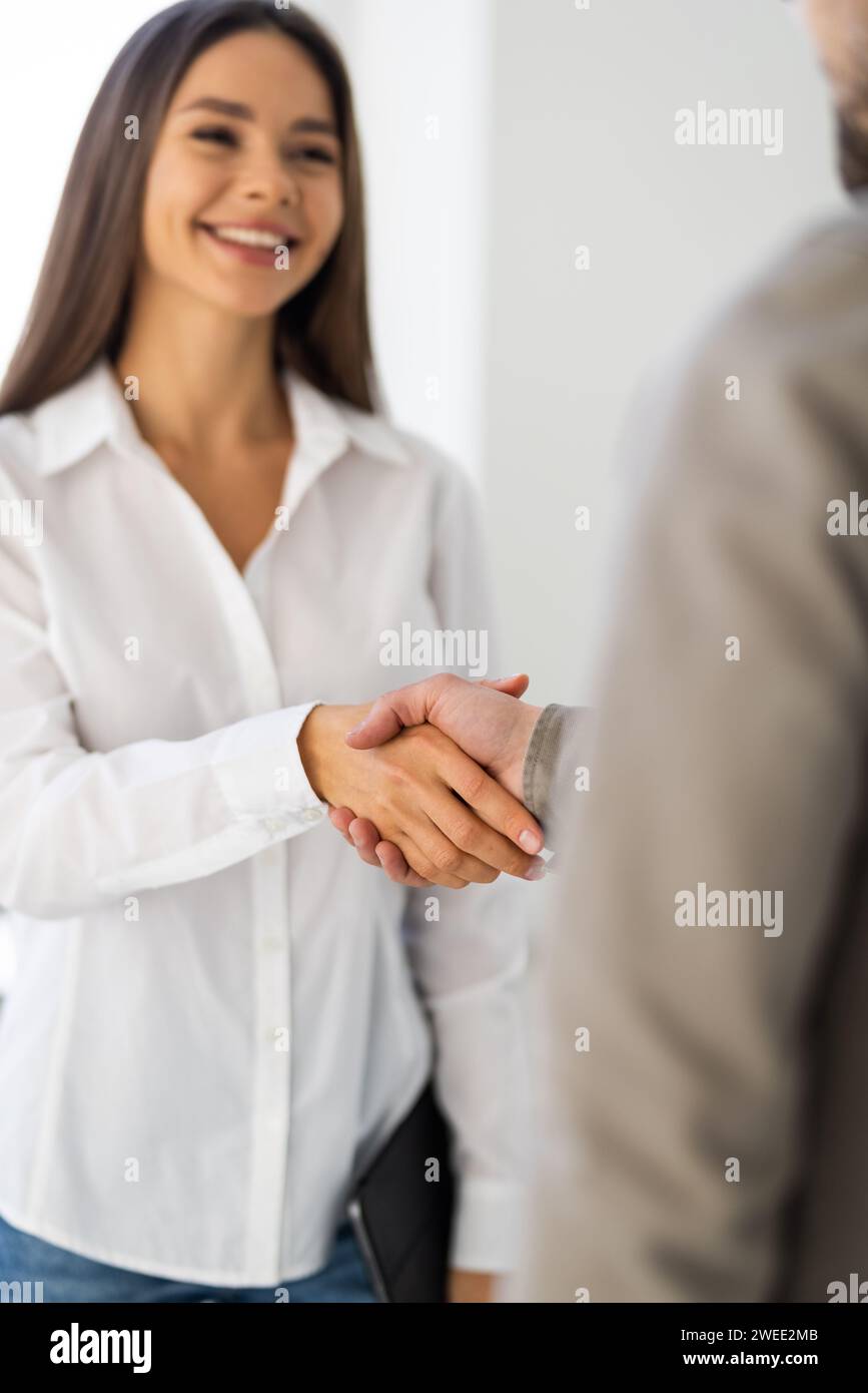 Young business couple handshaking in the office in front of their team Stock Photo