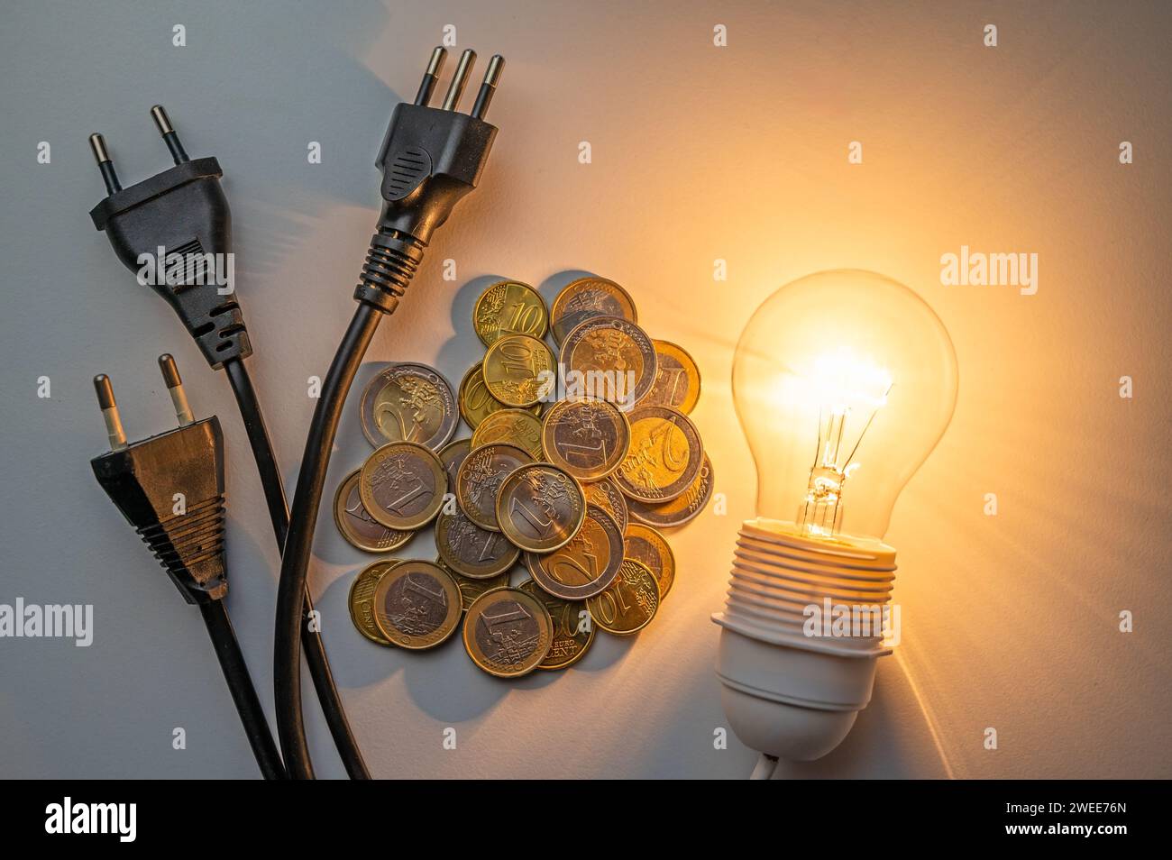 Light bulb lit with bills, coins, banknotes and electric plugs ...