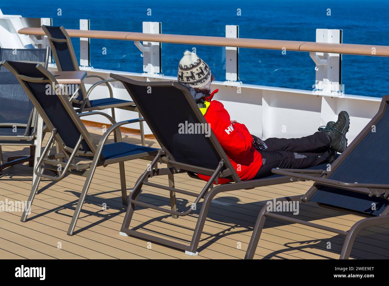 passenger watching the views while relaxing in lounger onboard Hurtigruten MS Fridtjof Nansen cruiseship cruise ship at Greenland in July Stock Photo