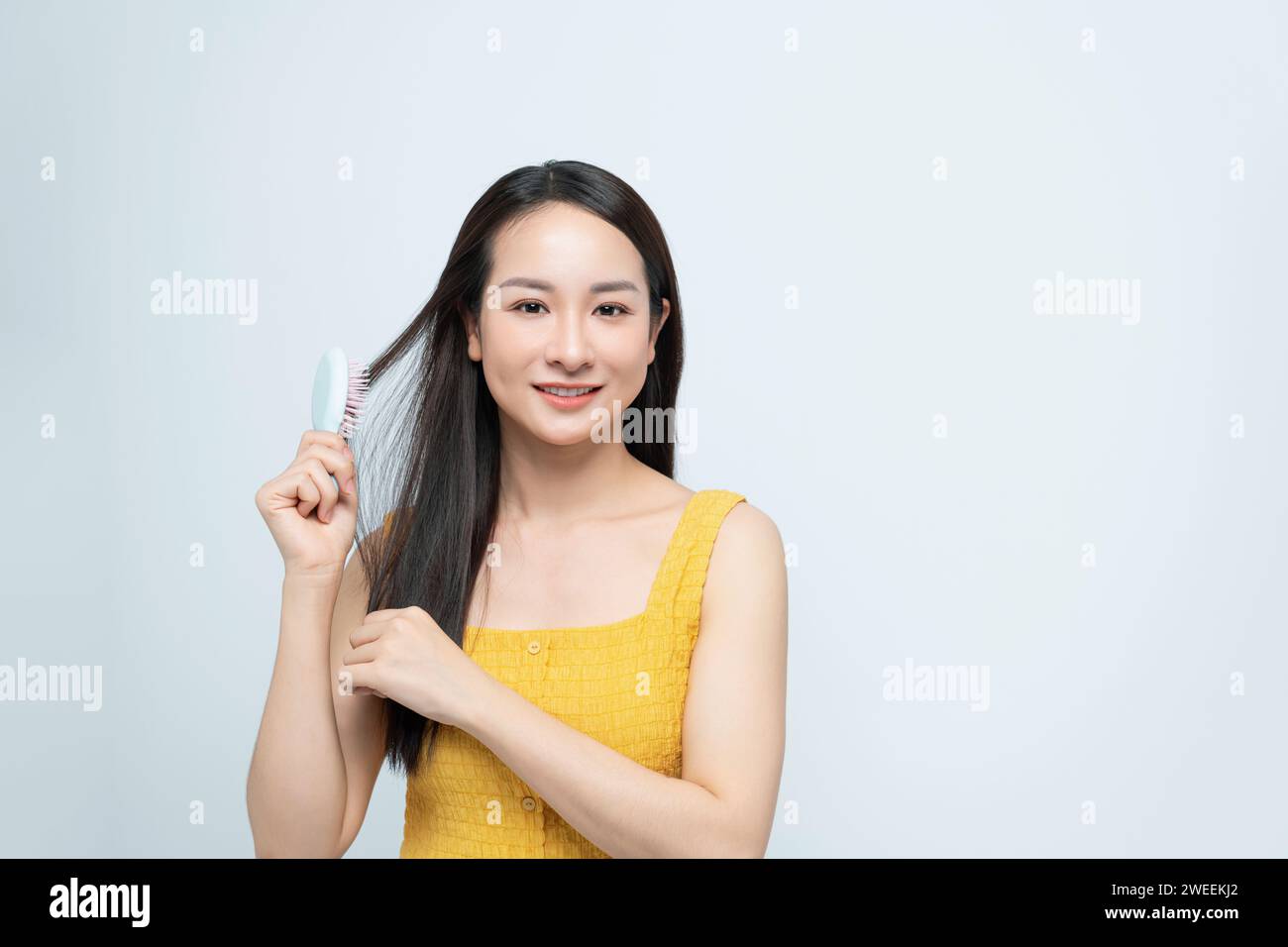 Attractive woman combing hair. Beautiful girl combs hair. Haircare concept. Stock Photo