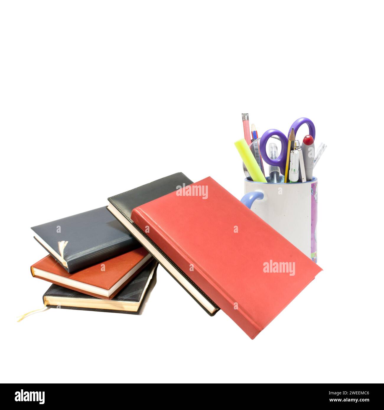 A diverse selection of stationery items, such as pens, markers, and paper clips, are arranged in a neat stack of books Stock Photo