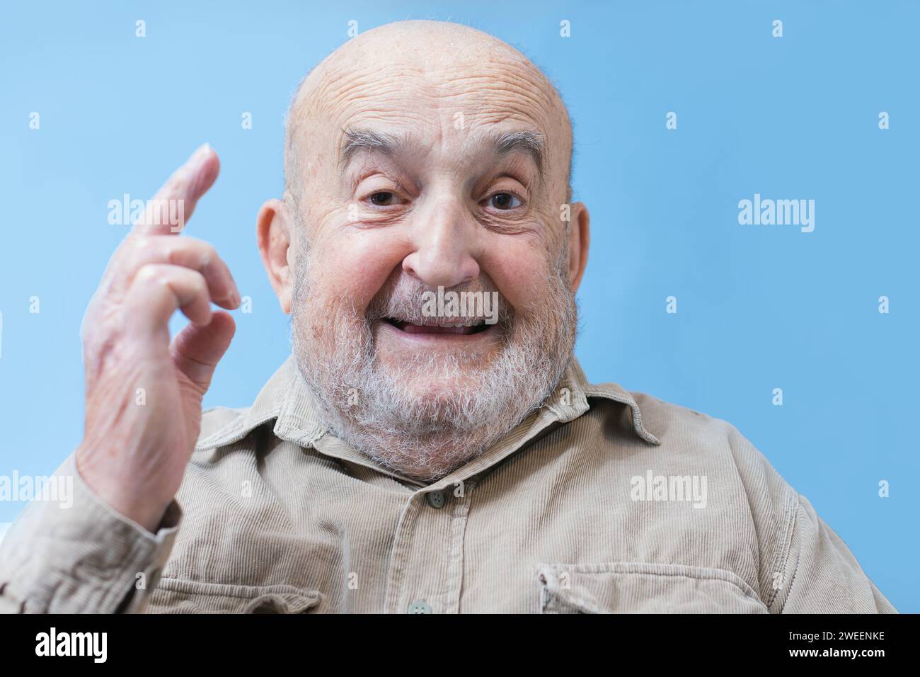 funny old man showing the middle finger isolated on blue background Stock Photo
