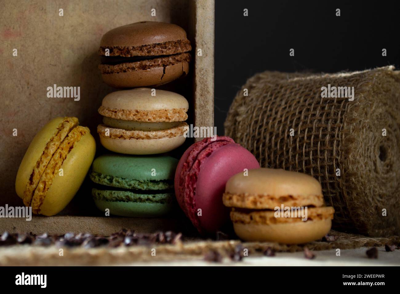 small multi-colored macaroons in a wooden box on a dark background Stock Photo