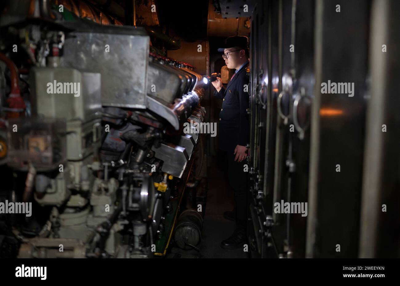 Harbin. 25th Jan, 2024. Driver Xu Ruinan works at the mechanical room of the train K7065 from Harbin to Fuyuan in northeast China's Heilongjiang Province, Jan. 23, 2024. The train K7065/K7066 travels to and fro between the city of Harbin and Fuyuan in China's northeastern province of Heilongjiang. With a single journey time of nearly 15 hours, the train replaced old carriages with new ones having air conditioning system, offering a better travel experience for locals who visit friends or commute to work or study along the line. Credit: Xinhua/Alamy Live News Stock Photo