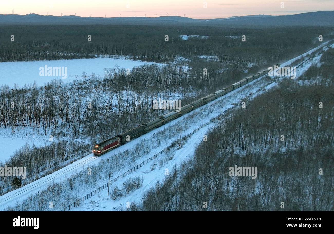 Harbin. 23rd Jan, 2024. Train K7066 runs along the railway from Fuyuan to Harbin in northeast China's Heilongjiang Province, Jan. 23, 2024. The train K7065/K7066 travels to and fro between the city of Harbin and Fuyuan in China's northeastern province of Heilongjiang. With a single journey time of nearly 15 hours, the train replaced old carriages with new ones having air conditioning system, offering a better travel experience for locals who visit friends or commute to work or study along the line. Credit: Wang Yuguo/Xinhua/Alamy Live News Stock Photo