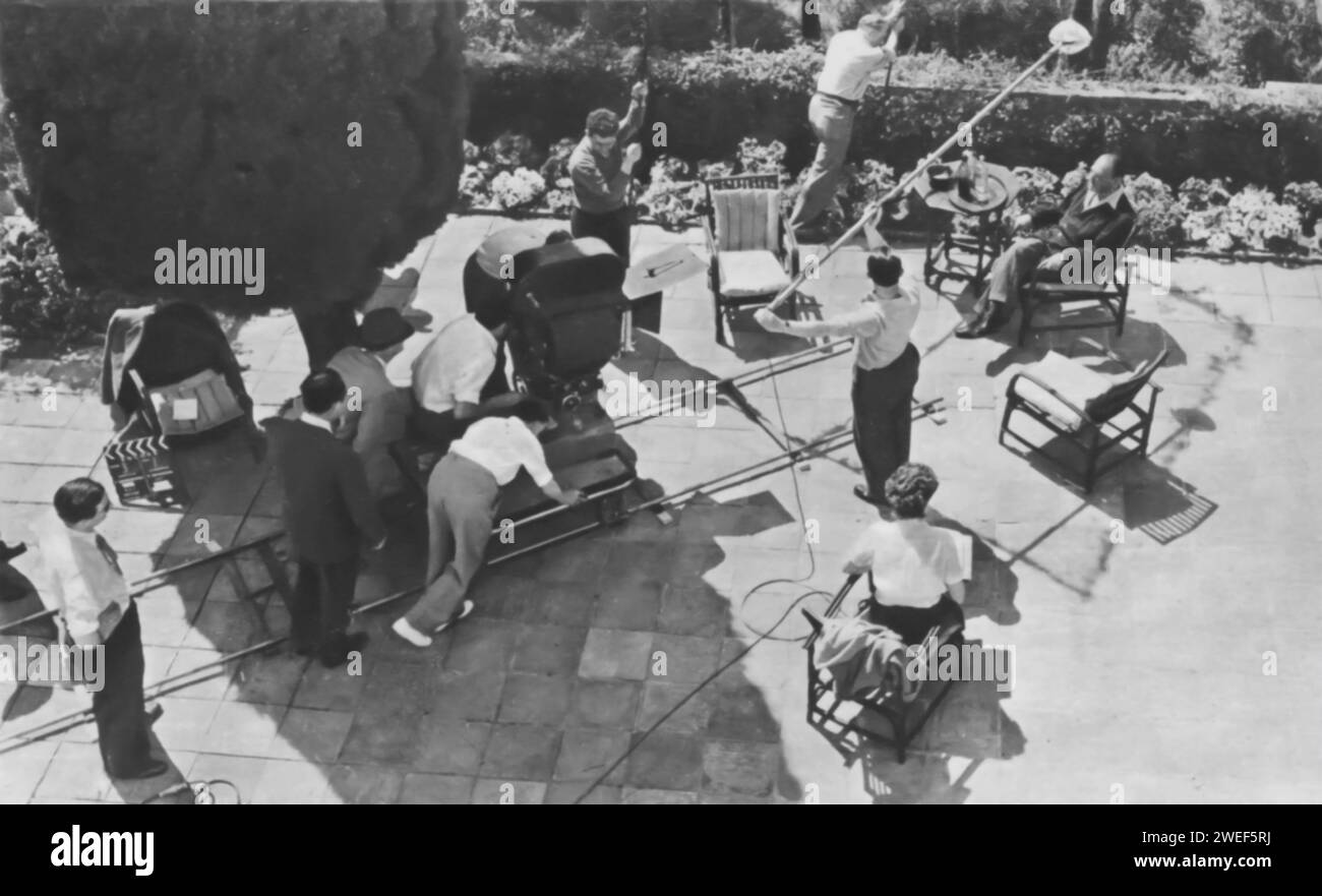 W. Somerset Maugham, the celebrated author, is shown on the set of 'Encore: Ant and the Grasshopper' at the Villa Mauresque garden. This segment of the anthology film 'Encore' (1951) is an adaptation of Maugham's short story 'The Ant and the Grasshopper.' The setting of Villa Mauresque, Maugham's own residence on the French Riviera, adds a touch of authenticity to the film. Stock Photo