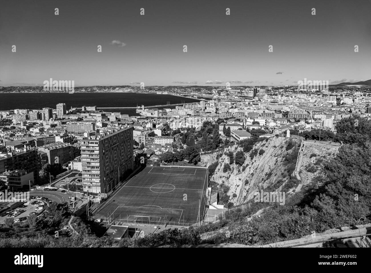 An aerial monochrome shot with a soccer field against a bustling cityscape Stock Photo
