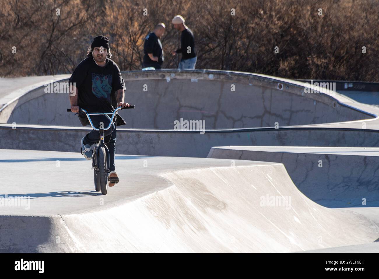 Sunny BMX ride: Boy on bike explores the skate park under the bright rays of a sunlit day. Stock Photo
