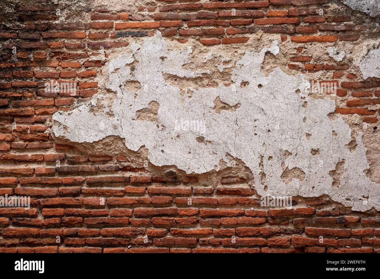 Old brick wall with large piece of stucco in the middle Stock Photo