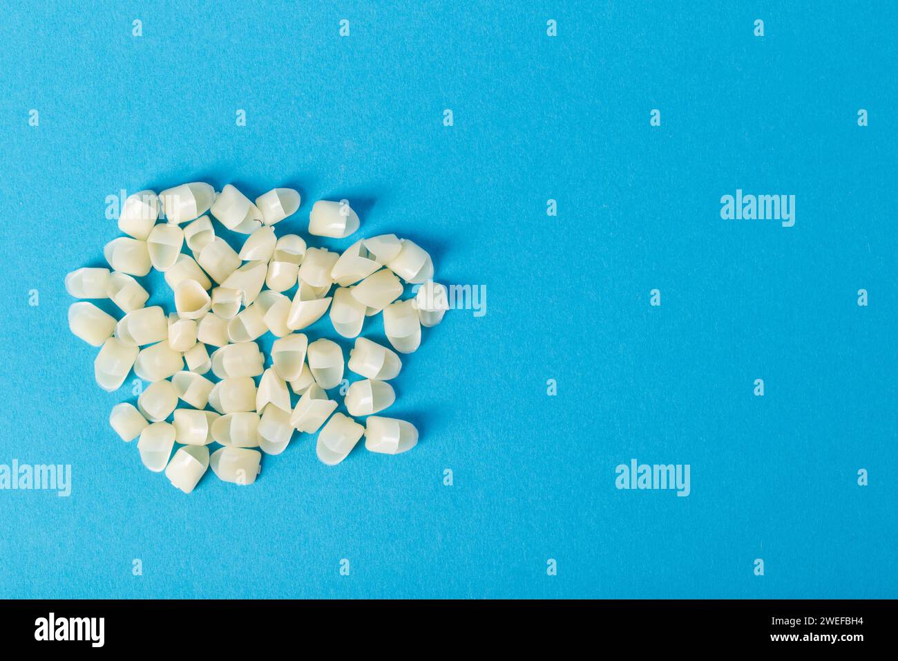 many dental crowns made of metal ceramics and zirconium on a blue background. The concept of