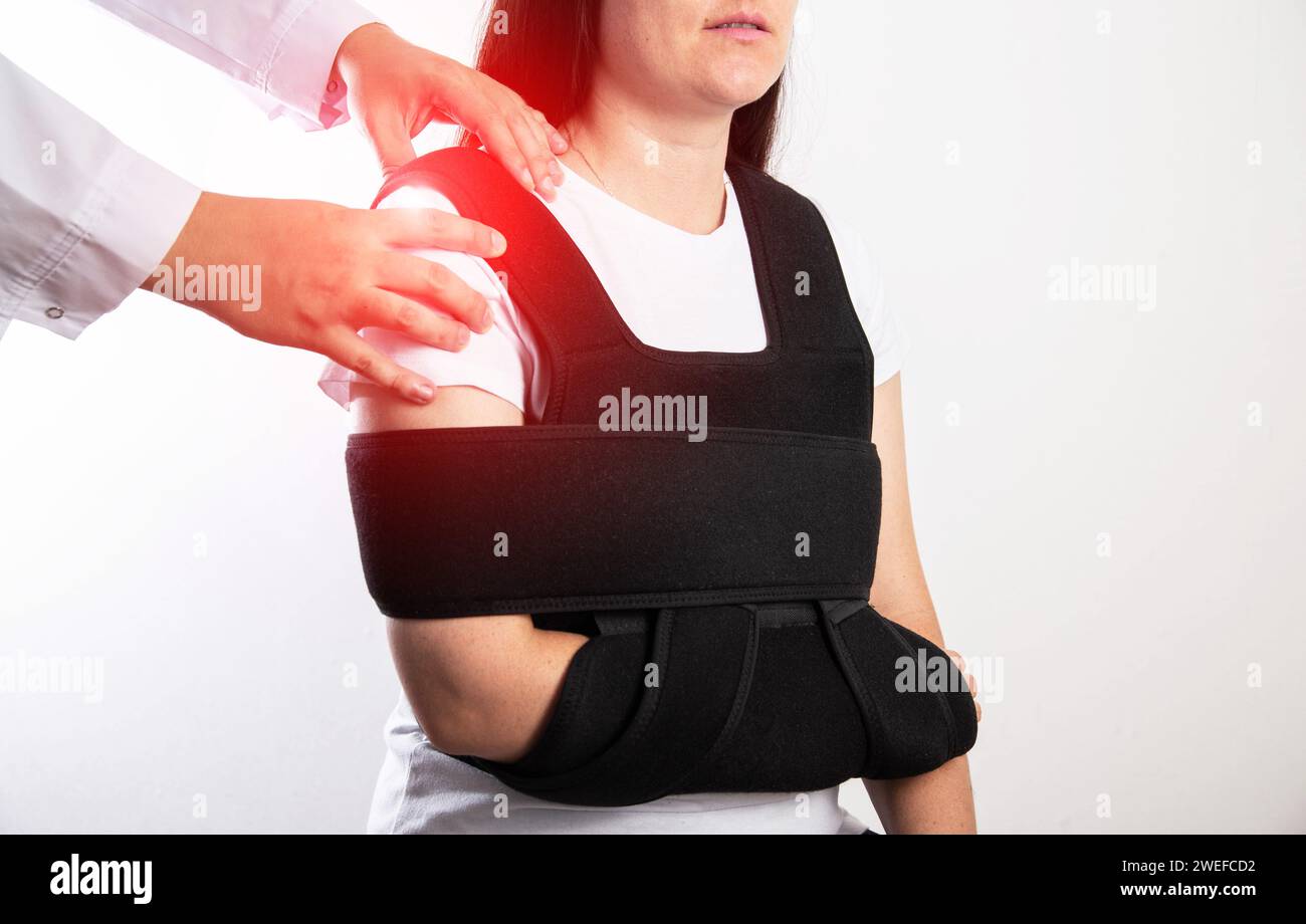 An orthopedic doctor examines a girl patient after a shoulder injury. Bandage on the shoulder joint after shoulder dislocation and bone fracture. Stock Photo