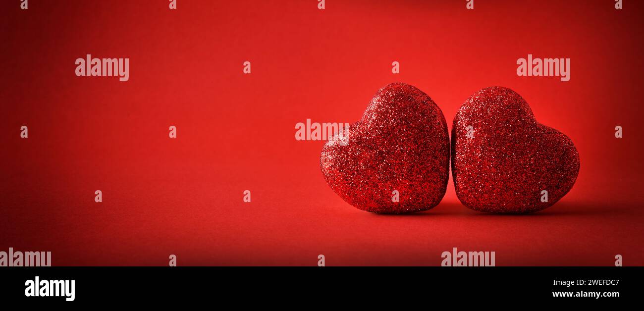 Background two red glitter hearts on red gradient background. Front view. Stock Photo