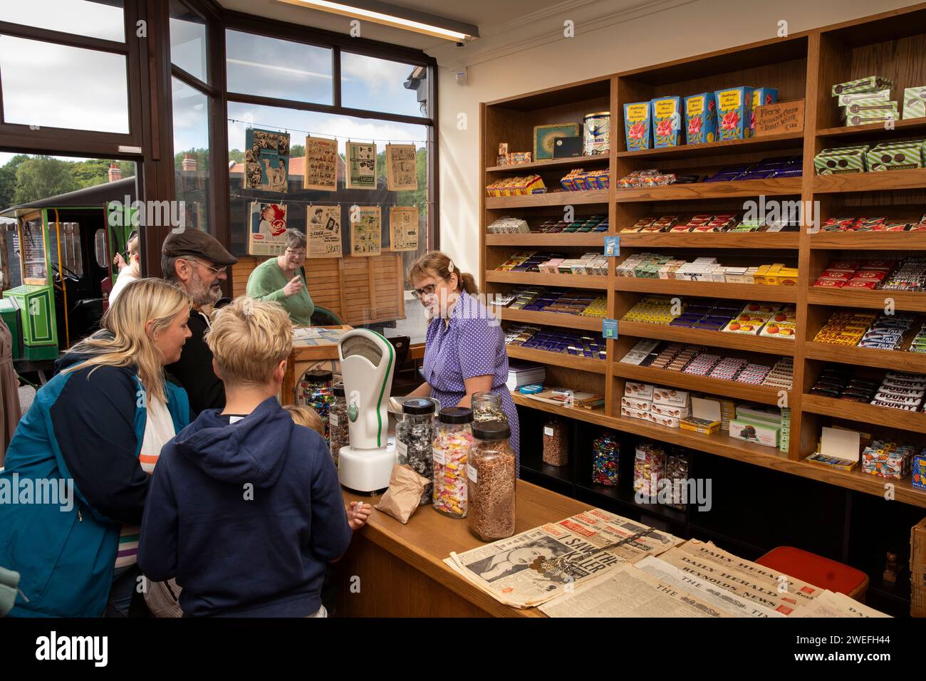 UK, England, West Midlands, Dudley, Black Country Museum, The Town, 1950s street, visitors inside Burgin’s newsagents Stock Photo