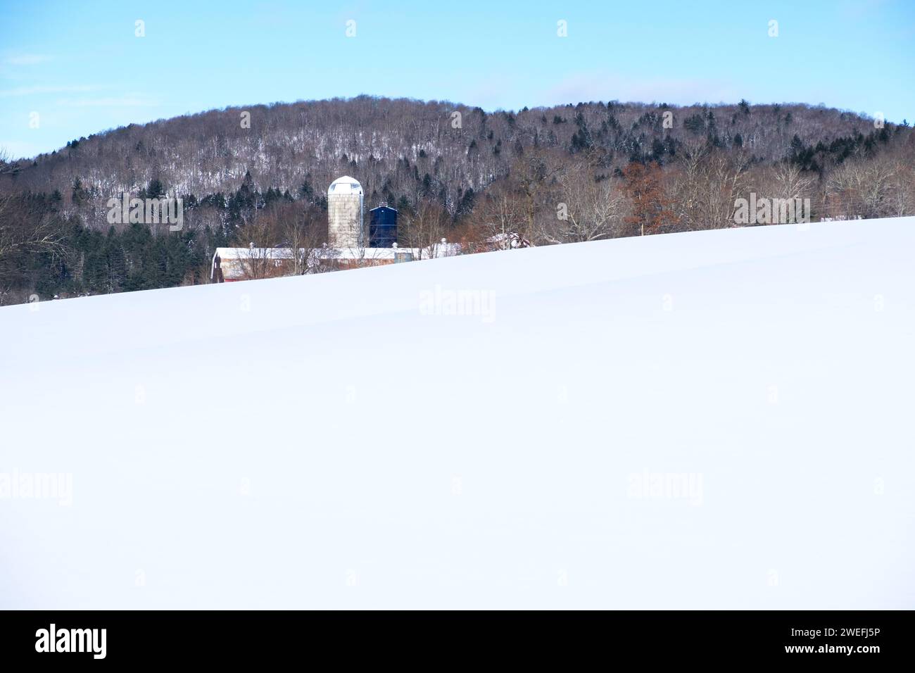 A barn and silo in a snowy field in East Montpelier, Vermont, USA, a