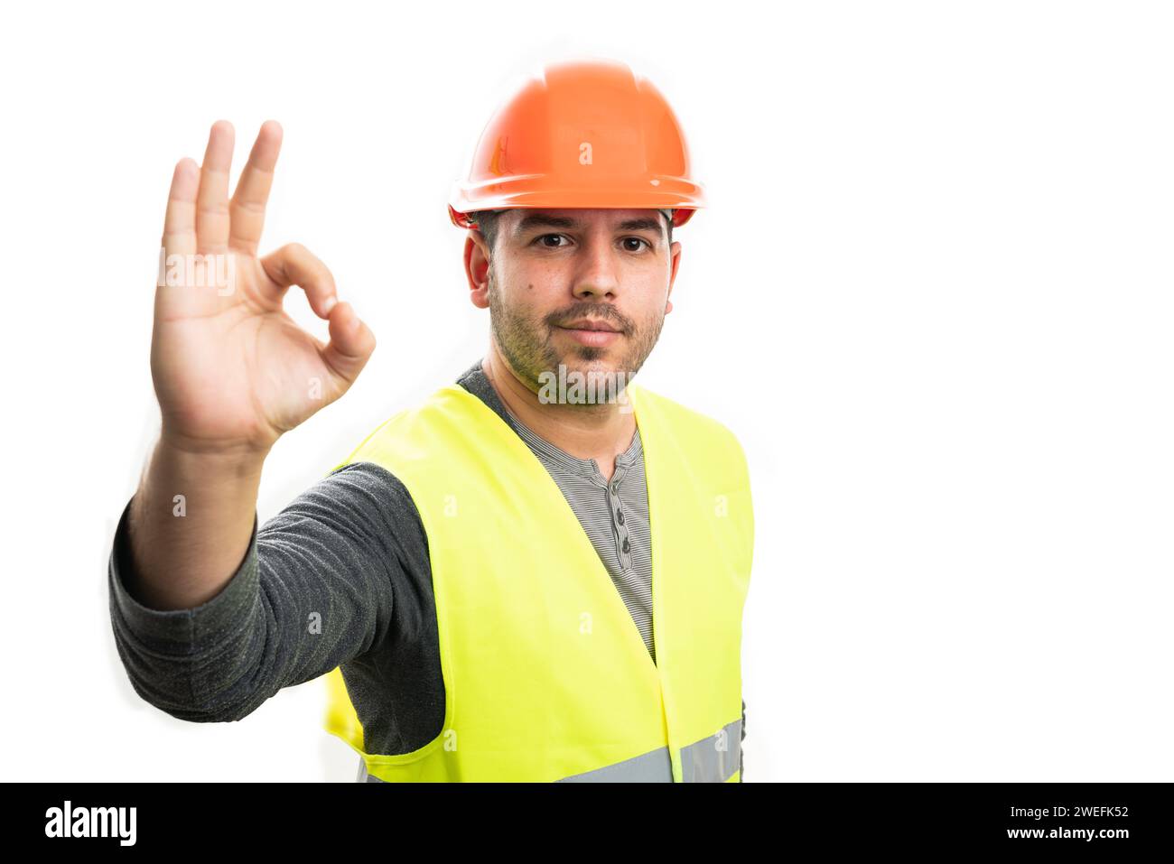 Adult builder man with friendly smiling expression showing okay gesture using fingers isolated on copyspace white studio background Stock Photo