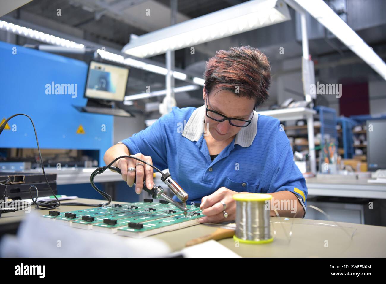 friendly woman working in a microelectronics manufacturing factory - component assembly and soldering Stock Photo