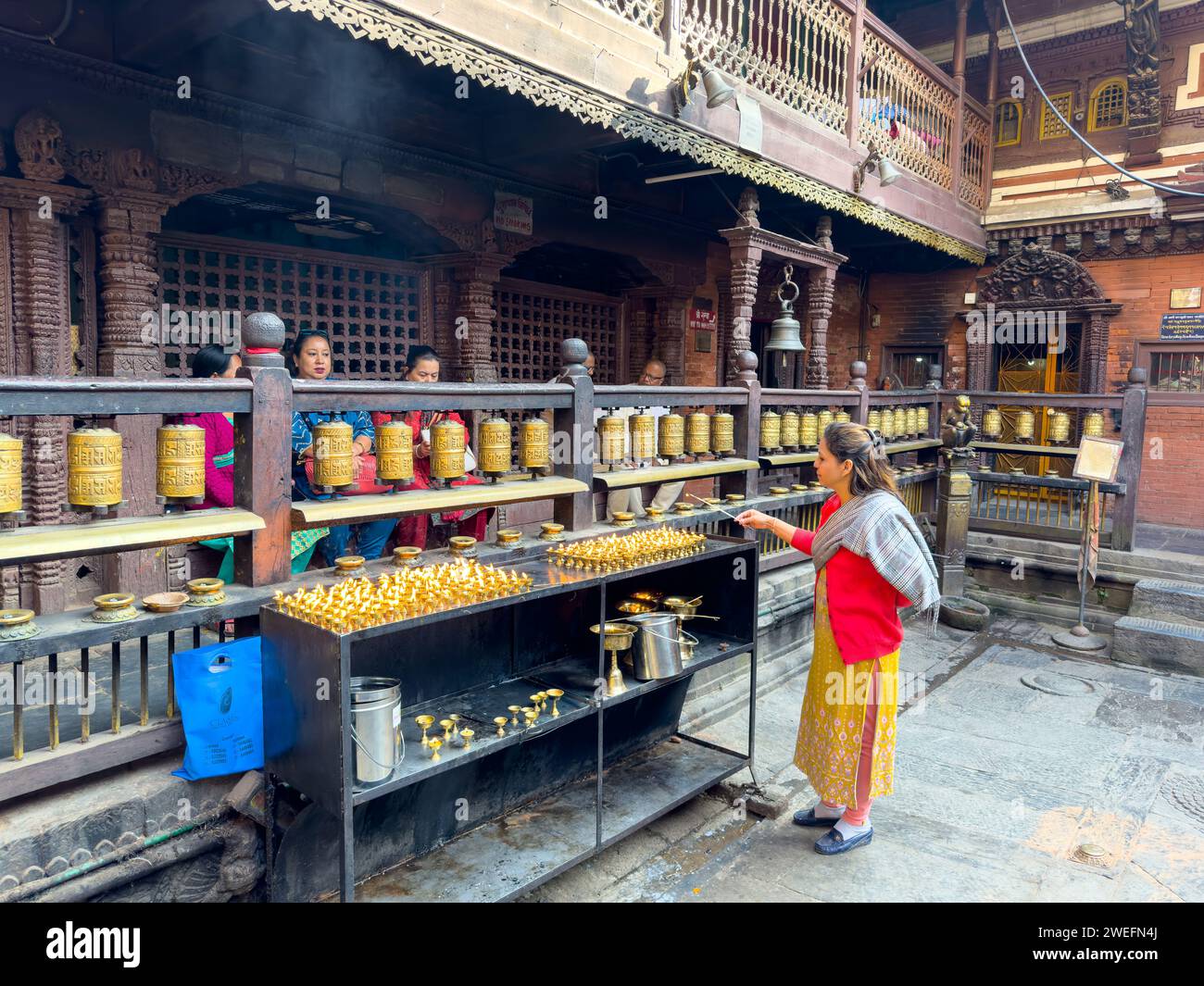 Woman lighting oil lamps at Hiraṇyavarṇa Mahāvihāra temple, formally ...