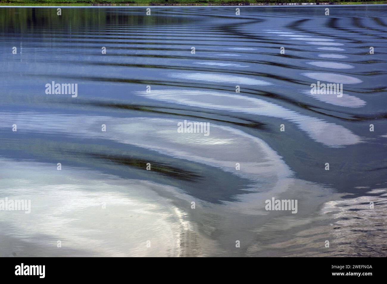 Gentle waves on the twin lakes in Musanze form abstract patterns on the surface of the water, with curves and a variety of colours Stock Photo