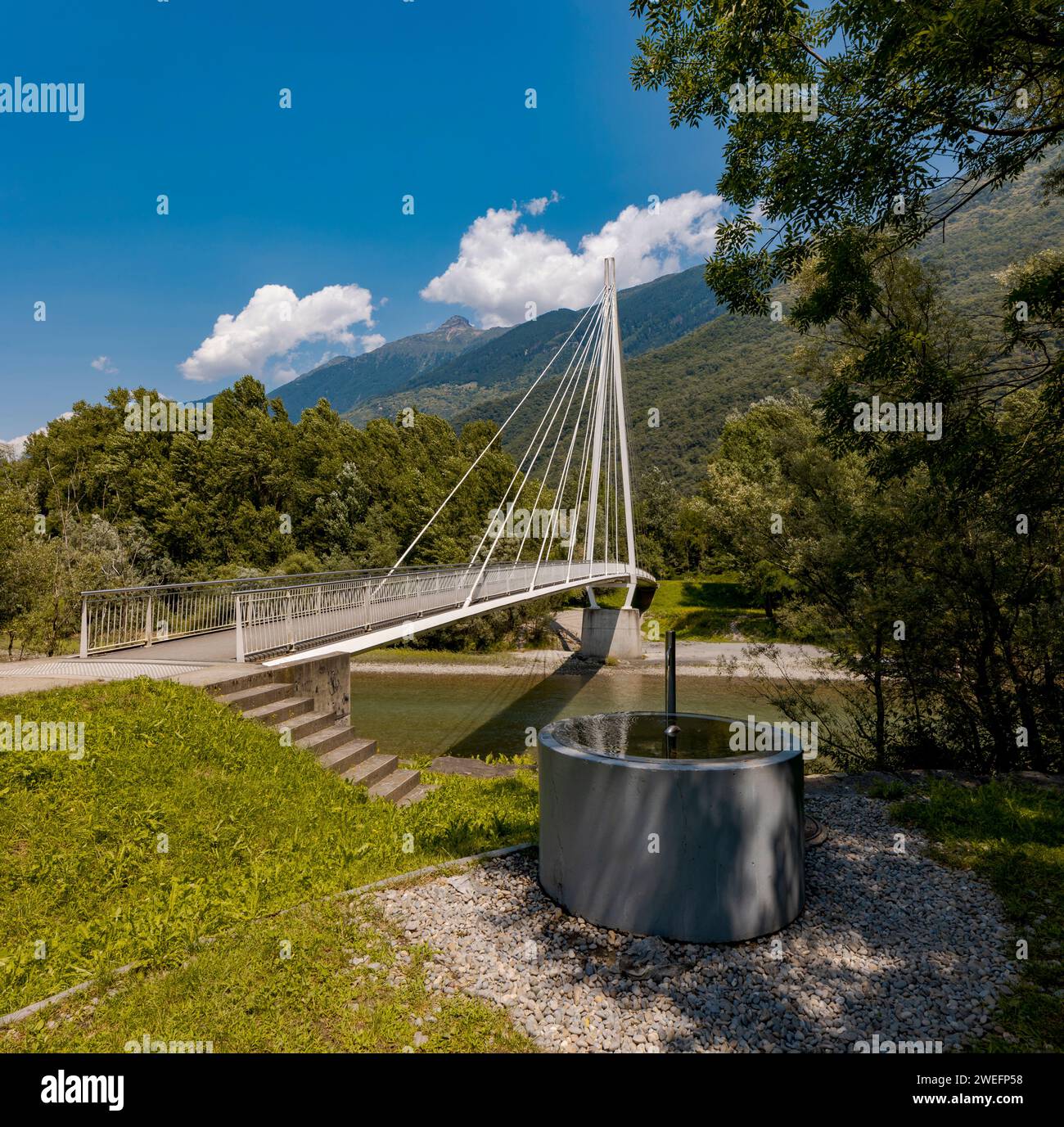 Modern pedestrian bridge in the middle of the mountains of Italian Switzerland, which allows you to cross the Ticino river. Beautiful sunny summer day Stock Photo