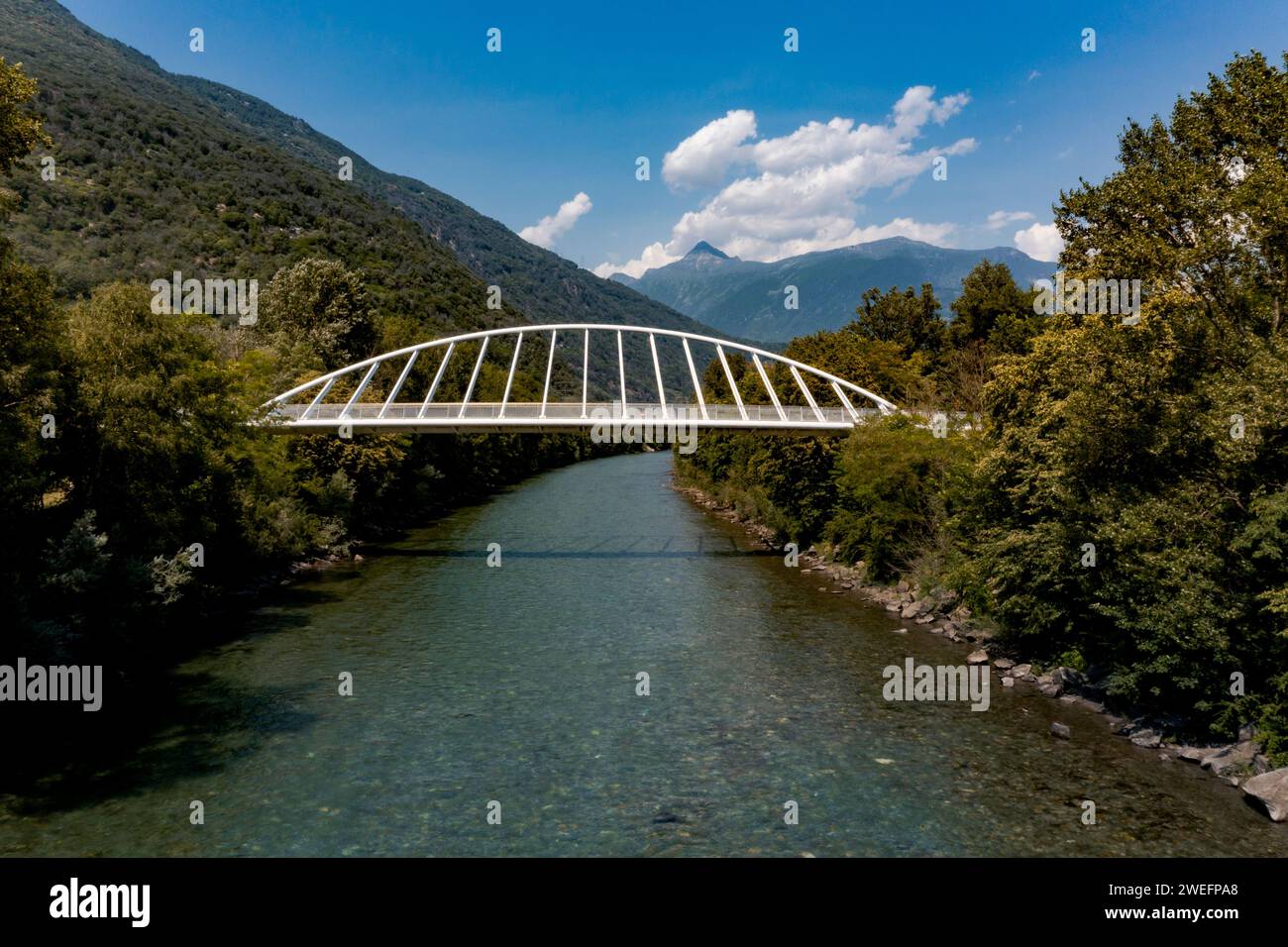 Pedestrian bridge over a small Swiss river, the Ticino. In summer, the footbridge is in the middle of nature with a very modern shape Stock Photo