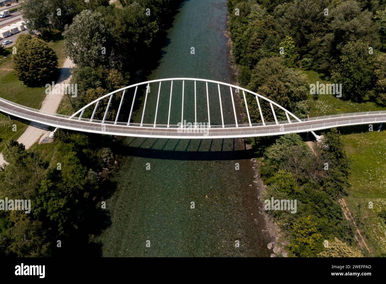 Aerial view of a modern arch shaped design pedestrian bridge over the Ticino river in Switzerland. Nobody inside Stock Photo