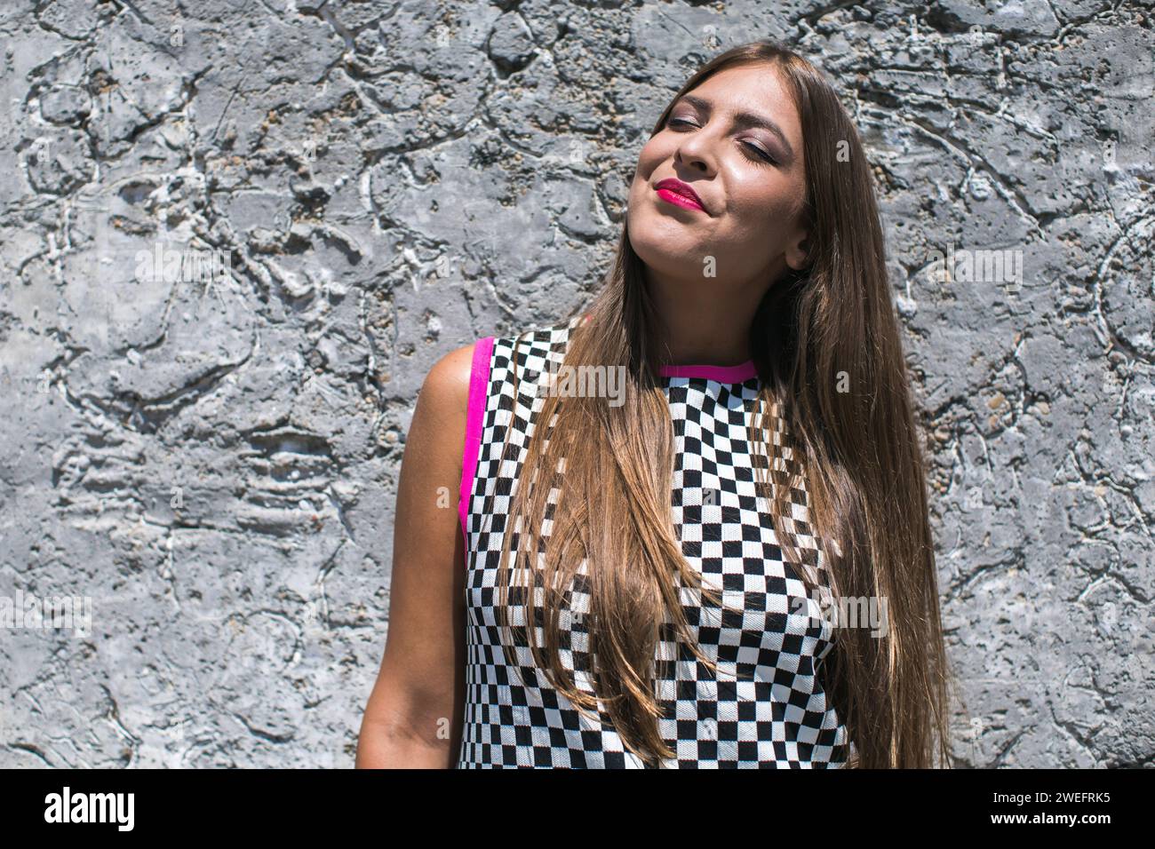 young woman dressed in chequered dress enjoying the sun Stock Photo