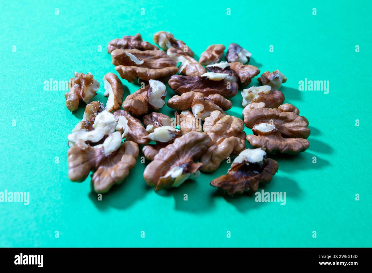 crashed walnuts isolated on green background Stock Photo