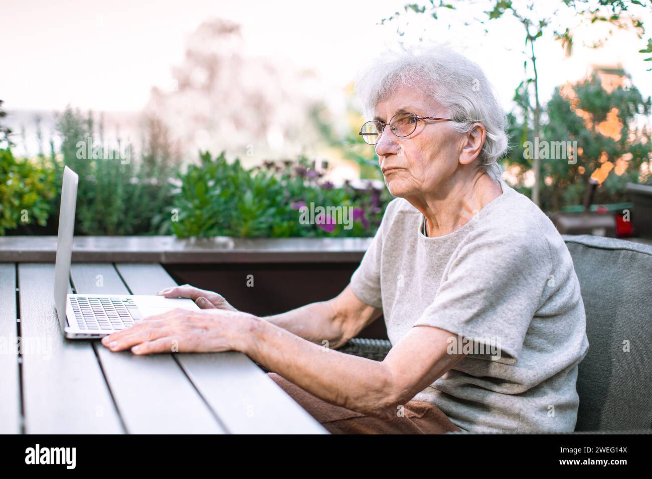 old woman using laptop on terrace Stock Photo