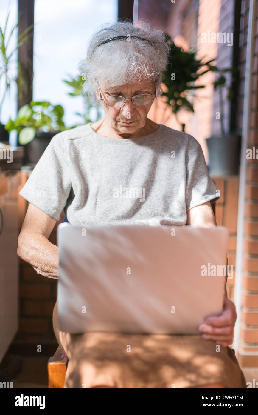 old woman using laptop on terrace Stock Photo