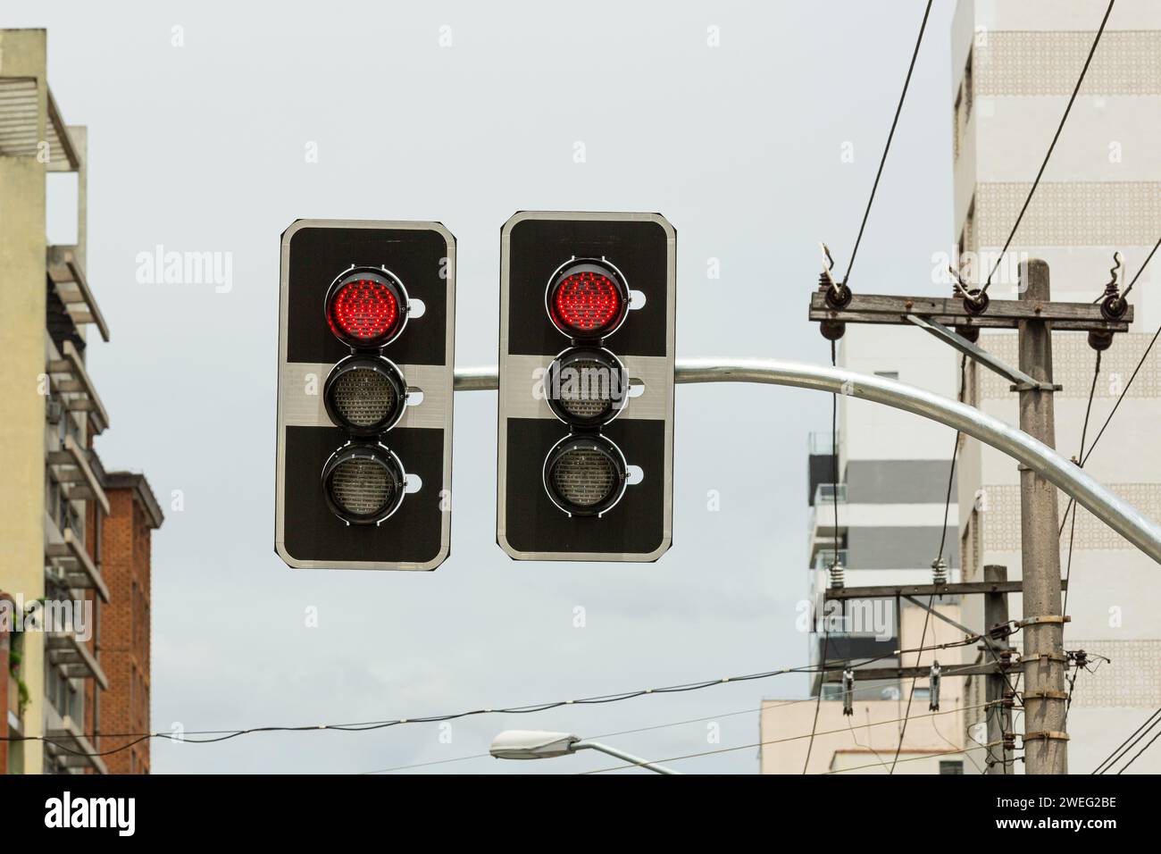 A pair of traffic lights with red lights on a cityscape background Stock Photo