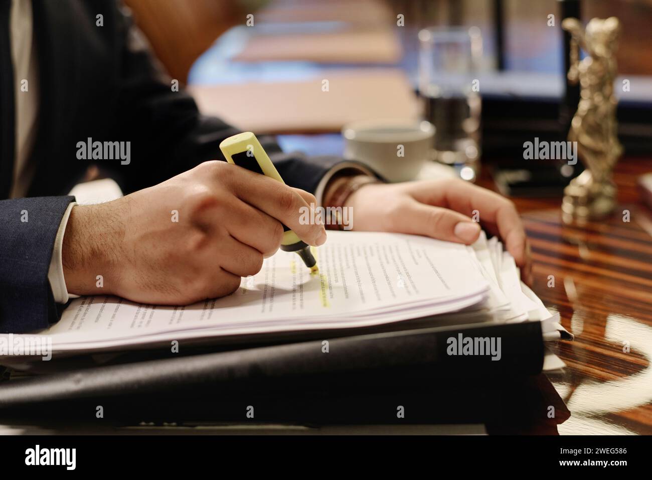 Closeup of male hands highlighting important information in document with yellow marker Stock Photo