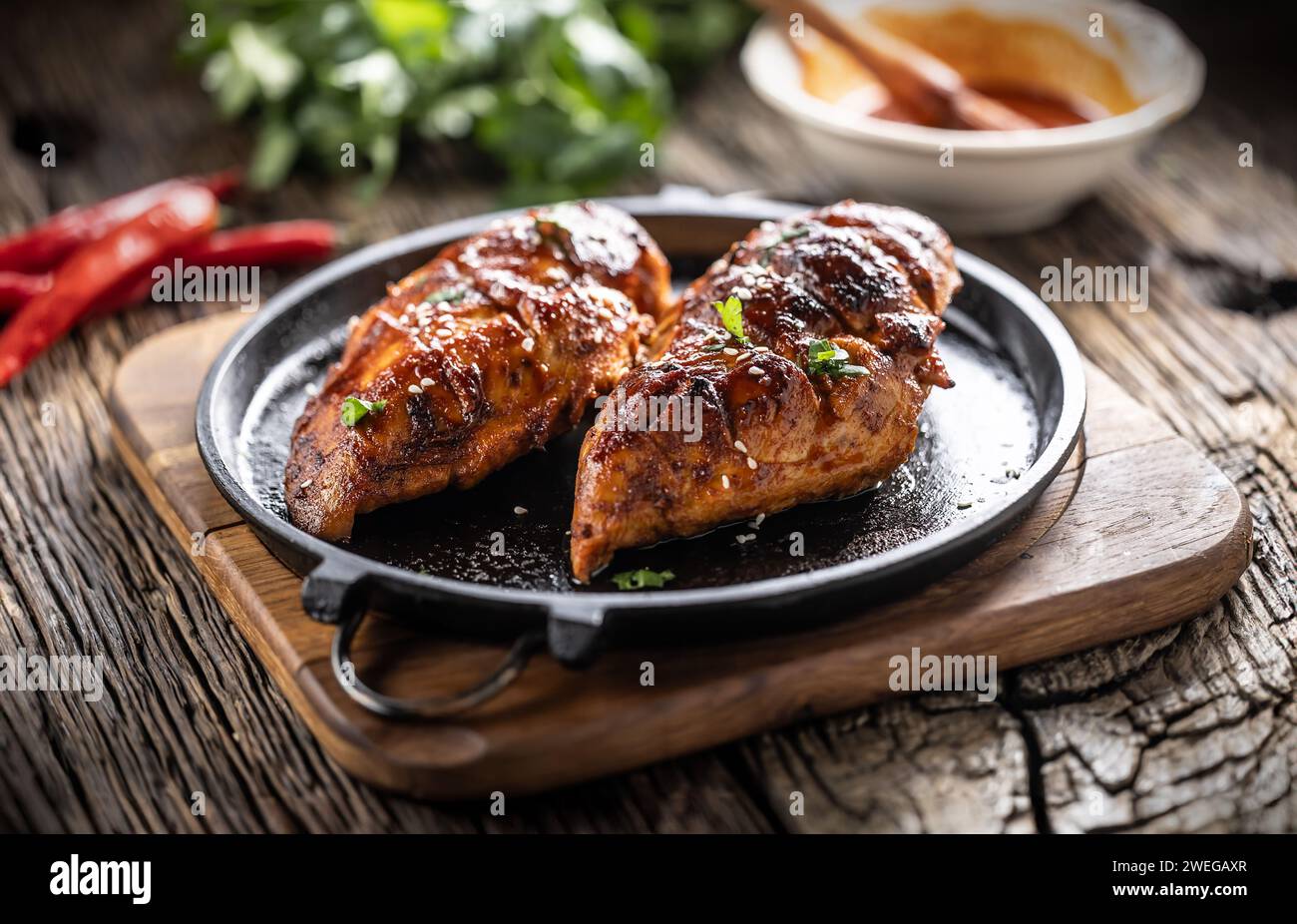 Marinated grilled chicken breast in BBQ sauce and served on a cast iron pan - Close up. Stock Photo