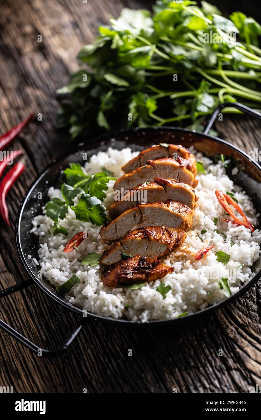 Grilled chicken breast served in a pan with jasmine rice and chili peppers. Stock Photo