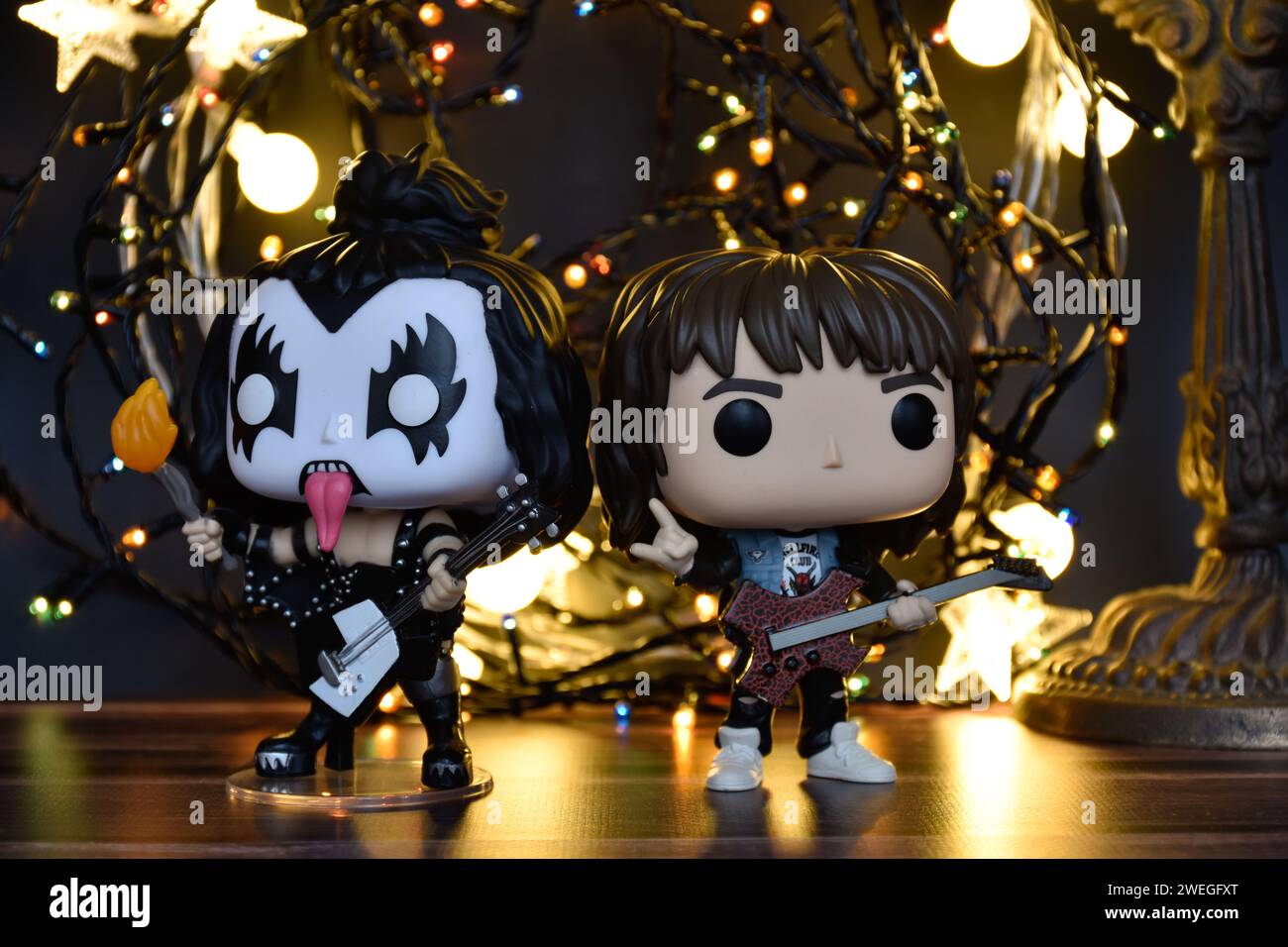 Funko Pop action figures of Gene Simmons The Demon, rock band Kiss and Eddie from TV series Stranger Things. Warm lighting, black background. Stock Photo