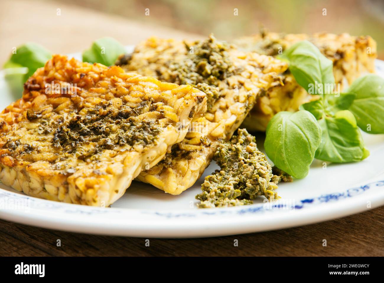 Slices of fried tempeh with a vegan arugula pesto. Stock Photo