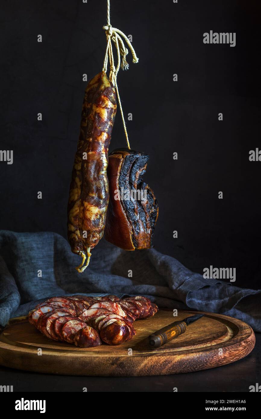 Hanging and cut homemade saussages and preserved meat on cutting board with linen napkin, traditionally prepared in Asian countries for lunar new year Stock Photo