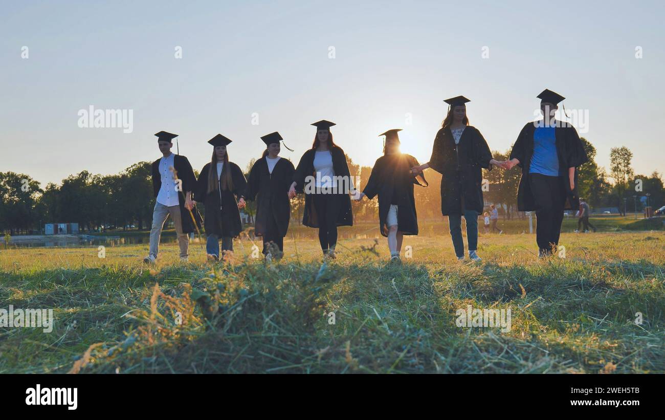 Graduate students walking through an evening meadow at sunset. Stock Photo