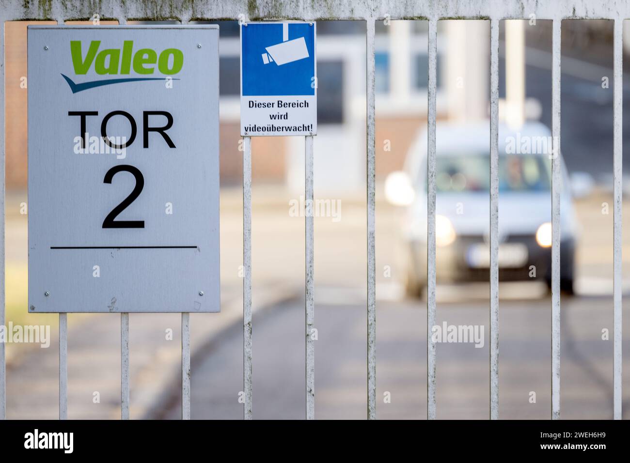 Ebern, Germany. 25th Jan, 2024. A car drives towards a factory gate of the automotive supplier Valeo. Credit: Pia Bayer/dpa/Alamy Live News Stock Photo