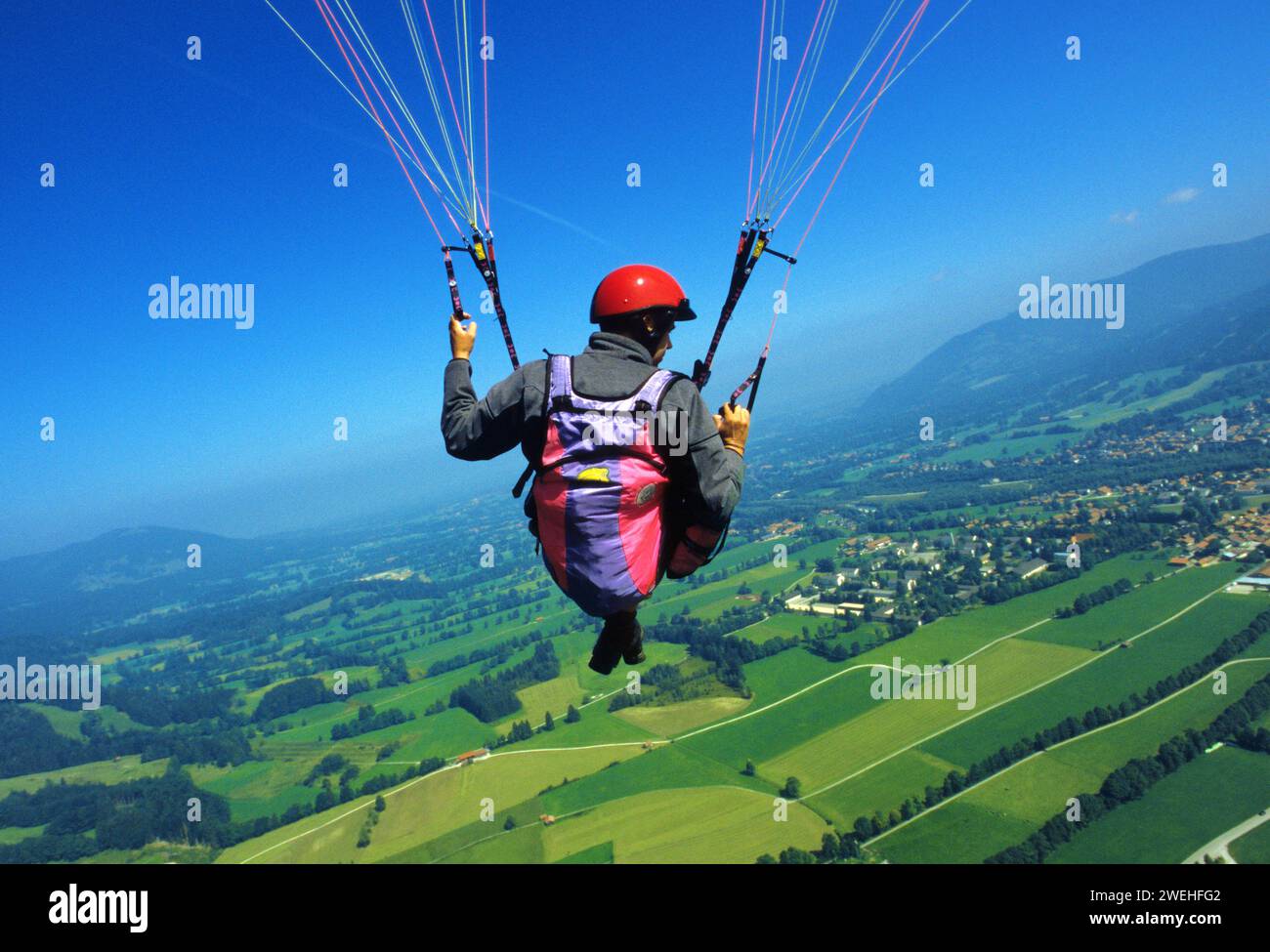 a man hangs from a paraglider high above the meadows near Lenggries, pilot's perspective, Bavaria, Germany, Europe Stock Photo