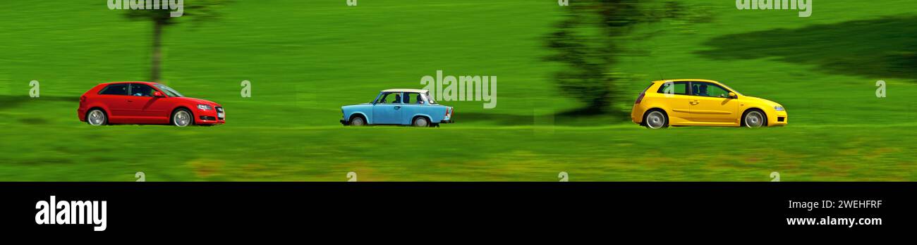 a red and a yellow car drive quickly through the green meadow landscape ...