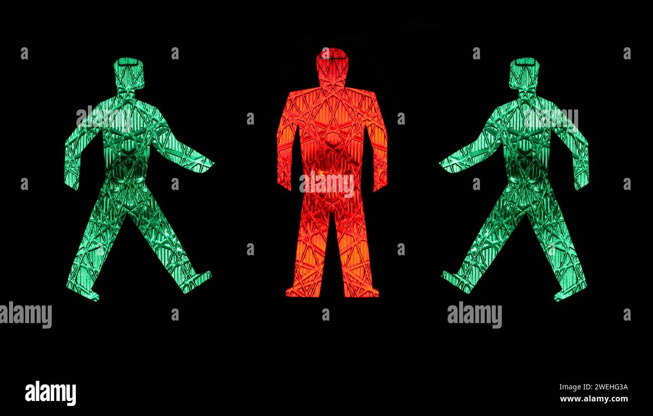 two green traffic light men walking towards a standing red one, pictograms, pedestrian lights Germany Stock Photo